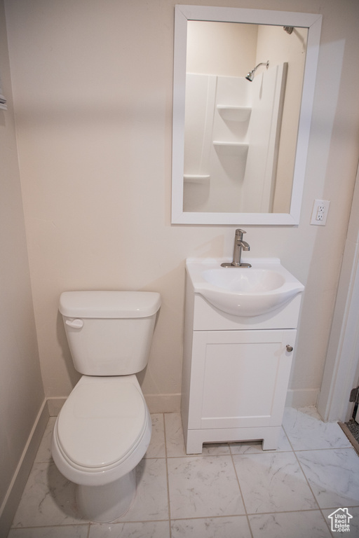 Full bathroom featuring marble finish floors, baseboards, toilet, vanity, and a shower
