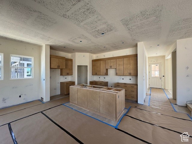 Kitchen featuring a kitchen island, brown cabinets, and a textured ceiling