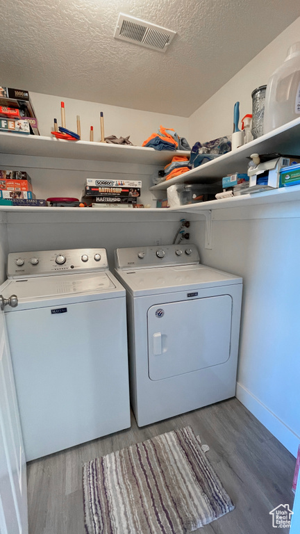 Clothes washing area featuring independent washer and dryer, hardwood / wood-style floors, and a textured ceiling