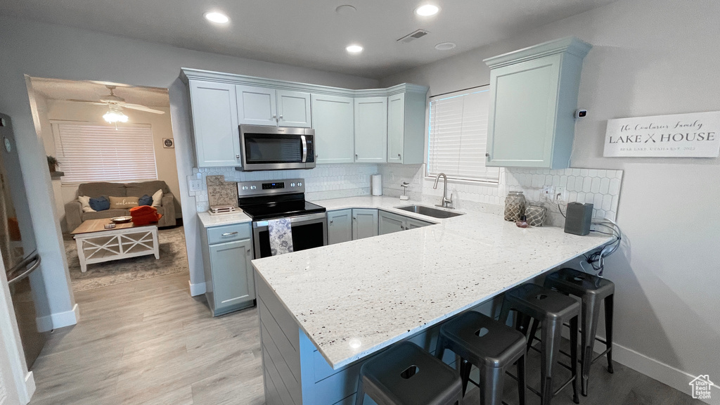 Kitchen with sink, decorative backsplash, kitchen peninsula, and appliances with stainless steel finishes