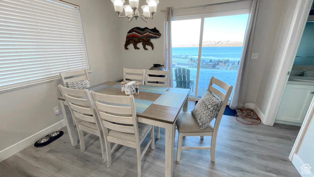 Dining area featuring a water view, an inviting chandelier, and light hardwood / wood-style floors
