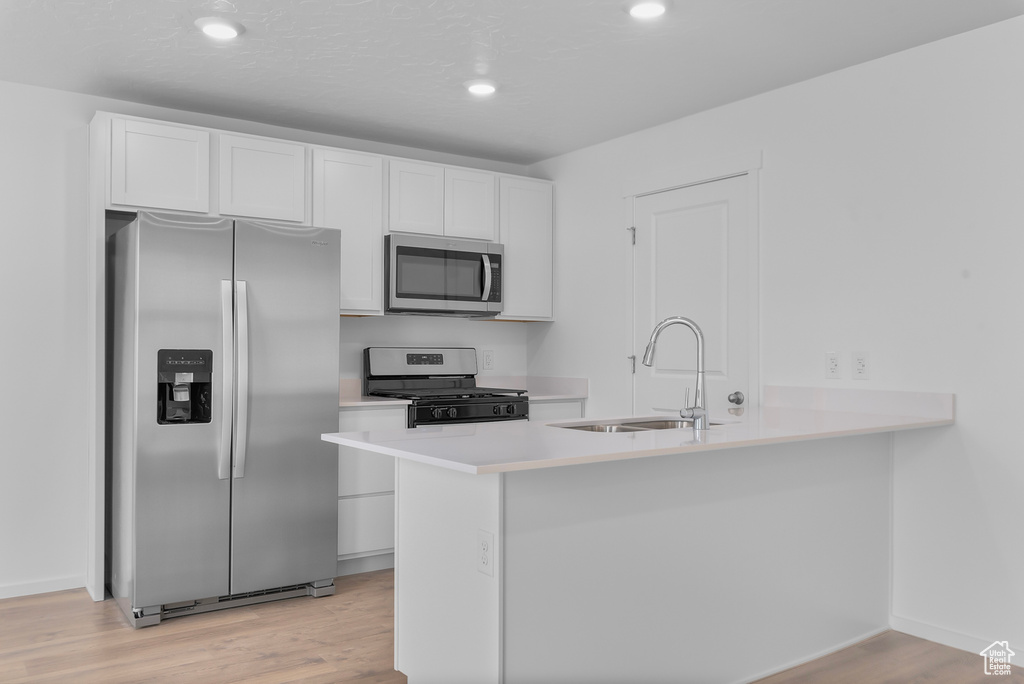 Kitchen featuring white cabinetry, sink, light hardwood / wood-style floors, and appliances with stainless steel finishes