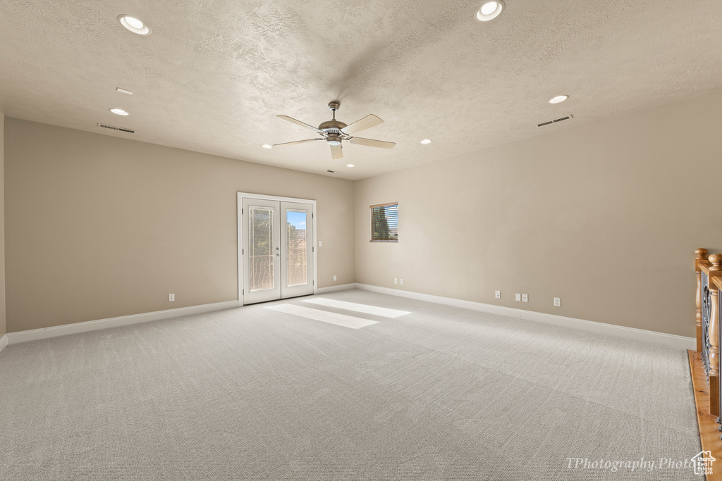 Unfurnished room featuring french doors, light carpet, and a textured ceiling