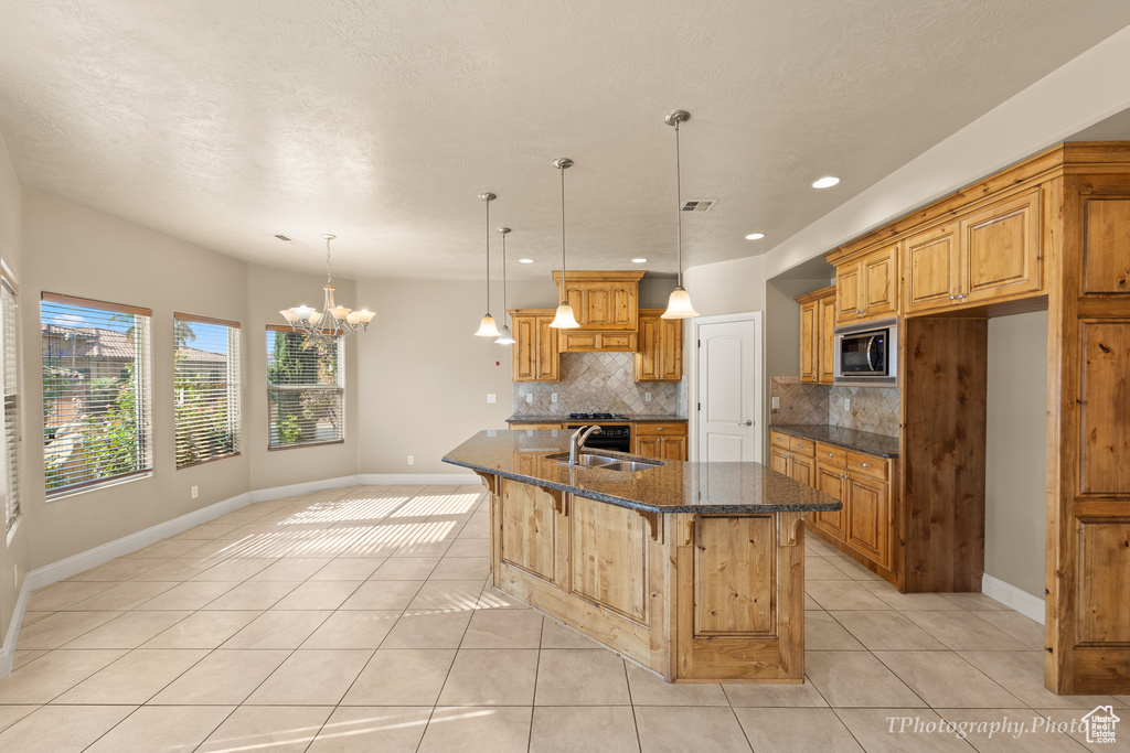 Kitchen featuring stainless steel microwave, light tile patterned floors, sink, and backsplash