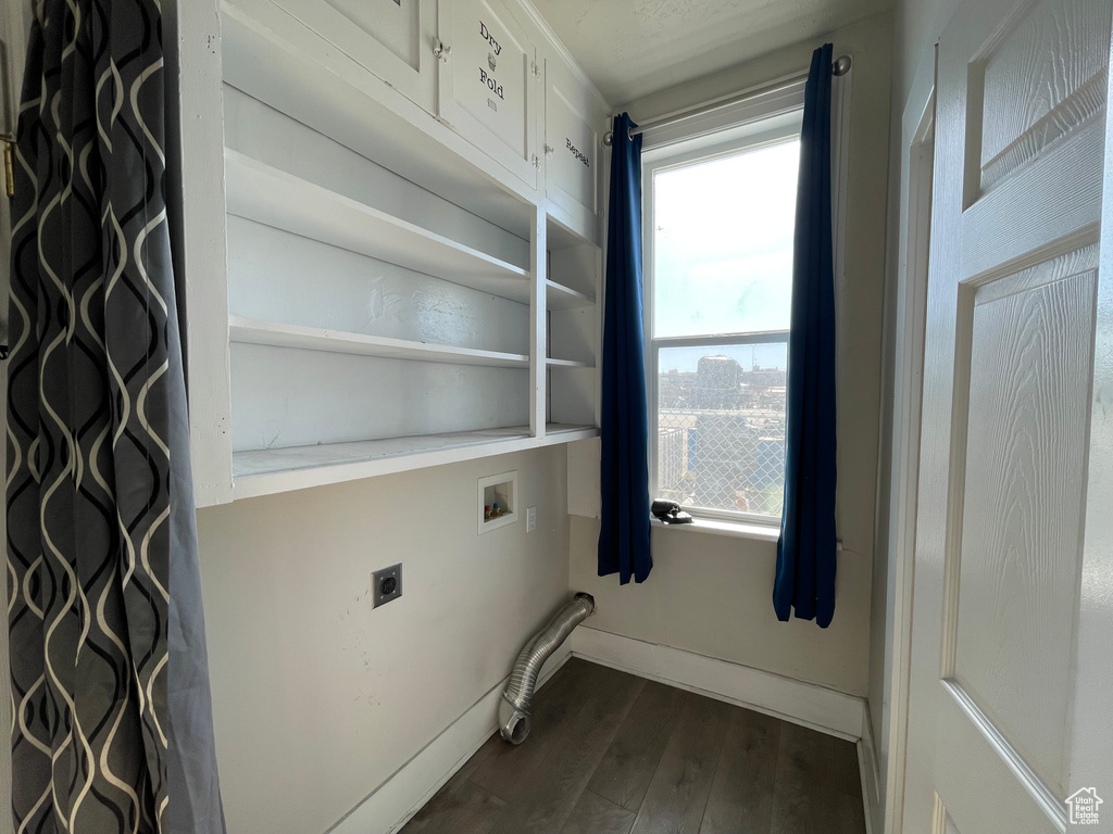 Laundry area with cabinet space, hookup for an electric dryer, dark wood finished floors, hookup for a washing machine, and baseboards