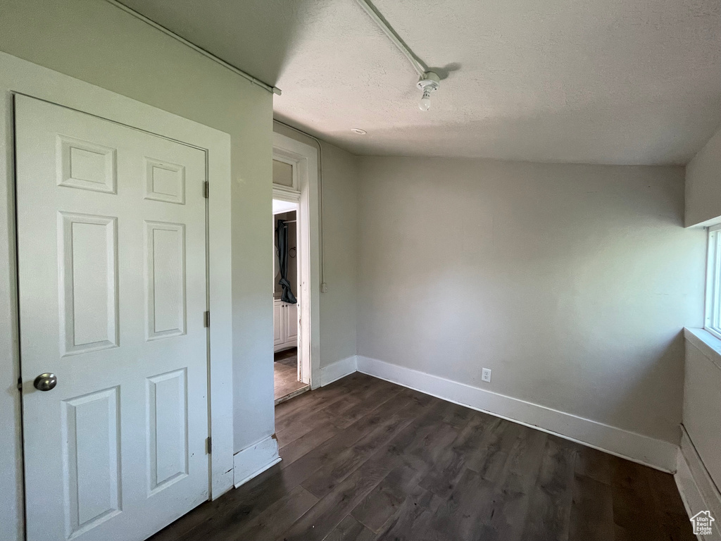 Empty room featuring baseboards, dark wood-type flooring, and a textured ceiling