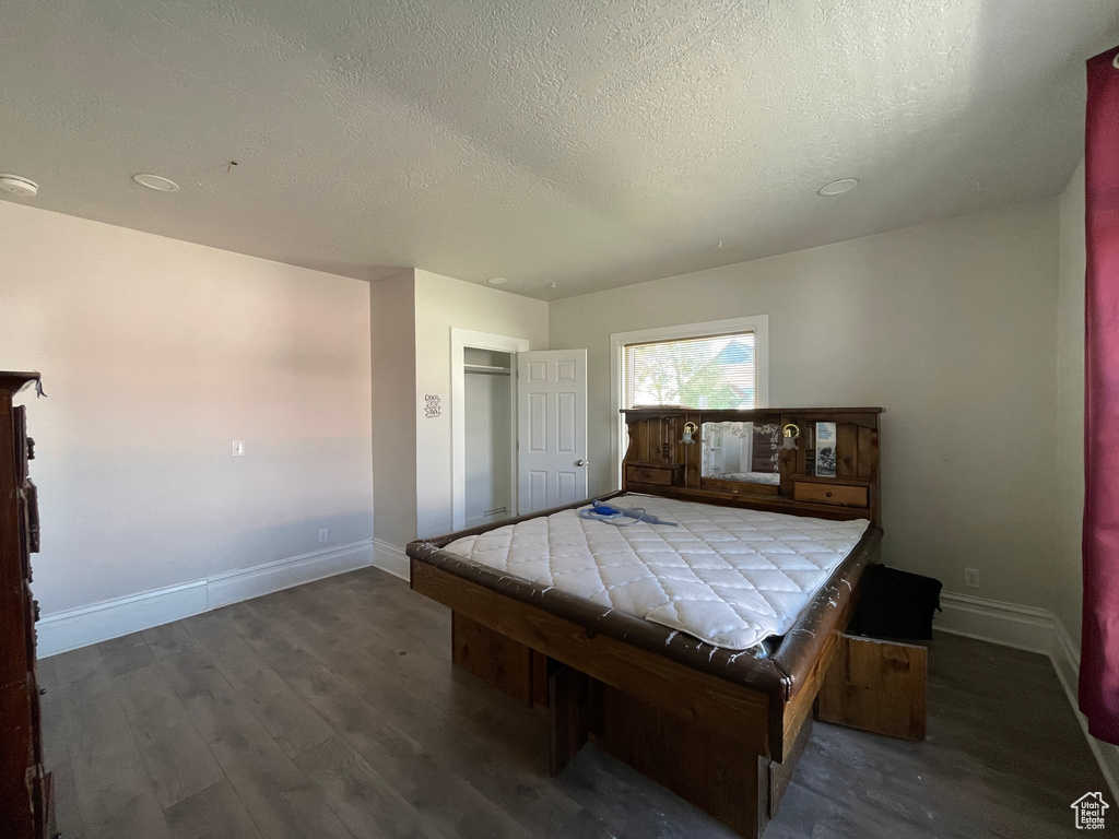 Bedroom with wood finished floors, a textured ceiling, baseboards, and billiards table