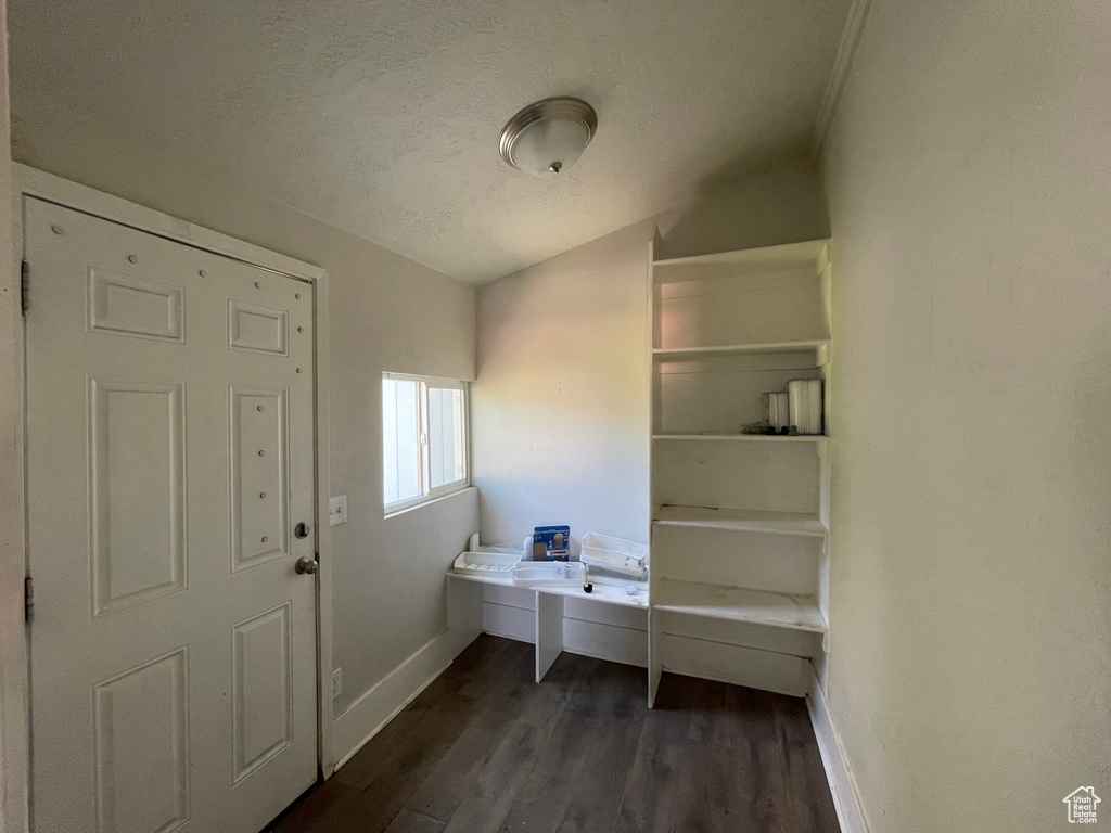 Foyer with baseboards, dark wood-type flooring, vaulted ceiling, and a textured ceiling