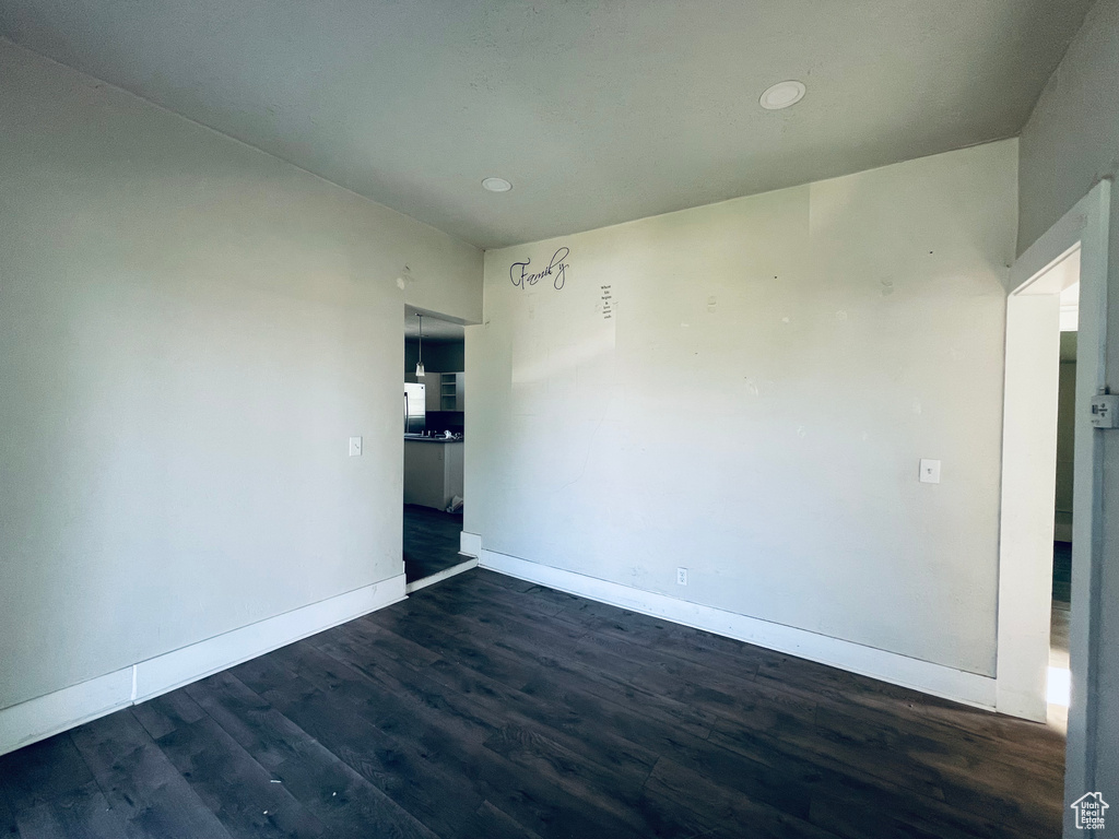 Spare room featuring baseboards, dark wood-type flooring, and recessed lighting