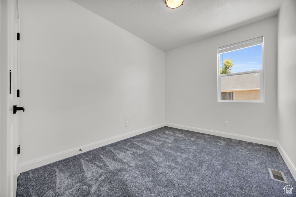 Empty room featuring dark colored carpet