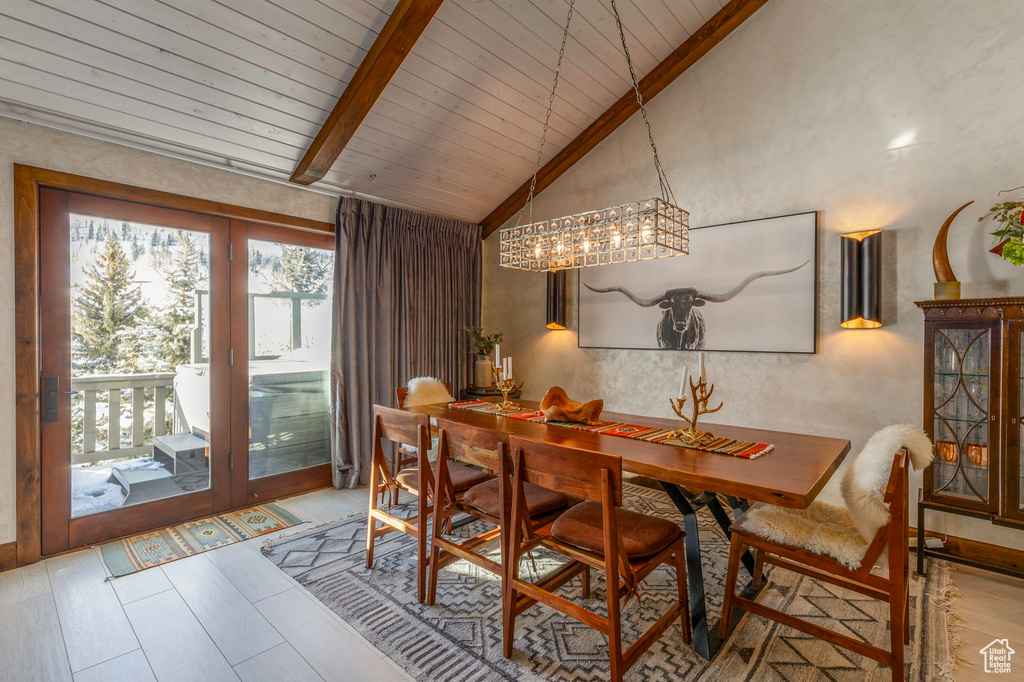 Dining area with wood ceiling with exposed beams, wood finished floors, a chandelier, and high vaulted ceiling