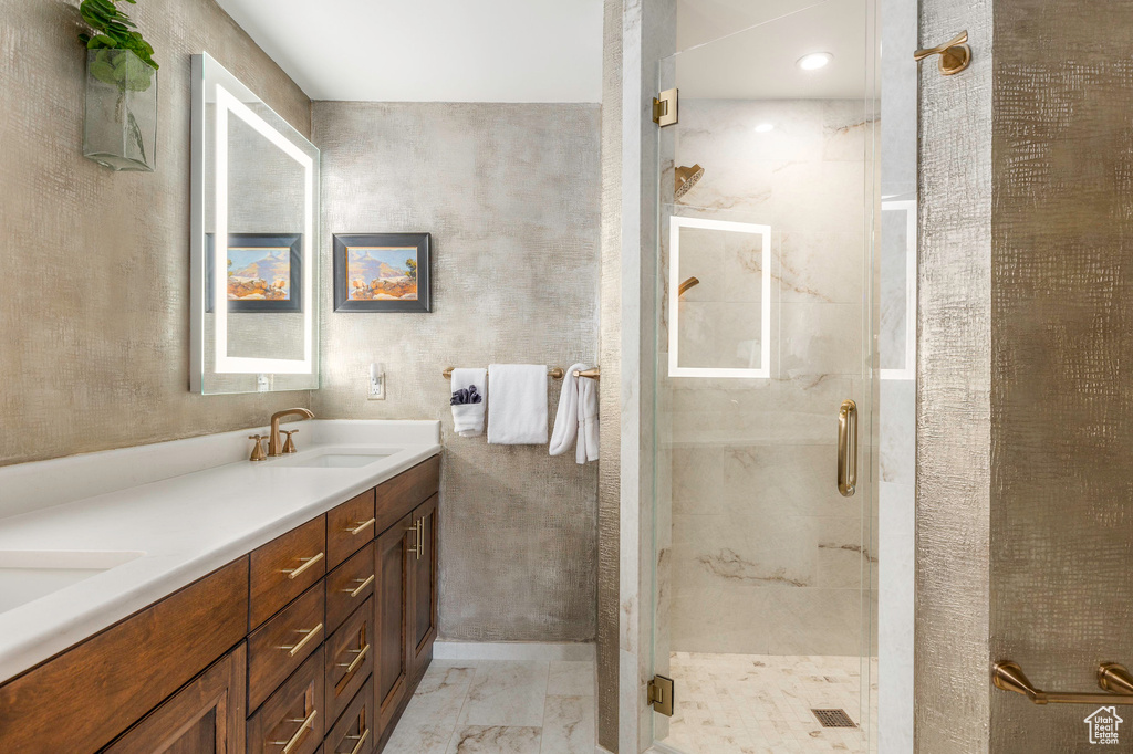Full bath with double vanity, a marble finish shower, and marble finish floors