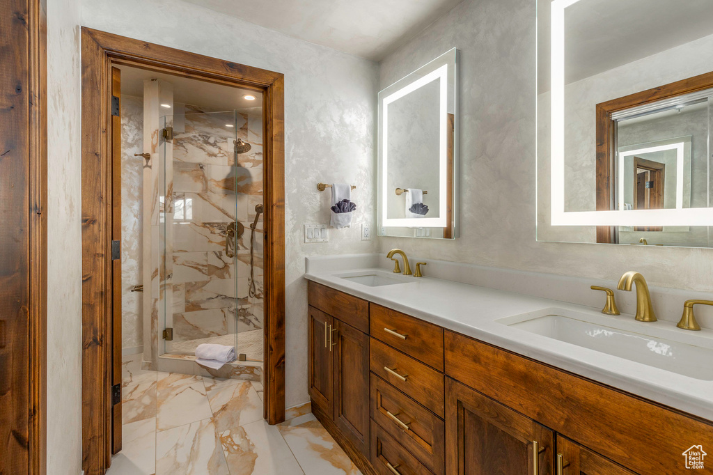 Full bath with a marble finish shower, double vanity, and marble finish floors
