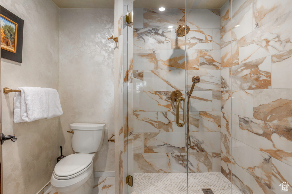 Full bath with a marble finish shower and toilet