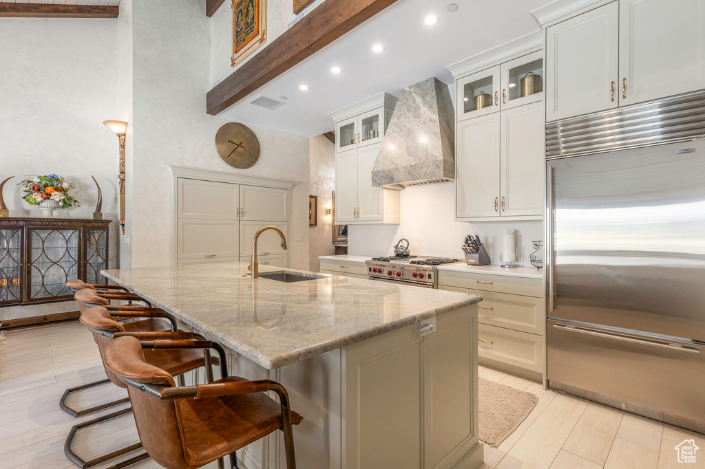 Kitchen featuring high end appliances, custom range hood, a sink, recessed lighting, and a center island with sink