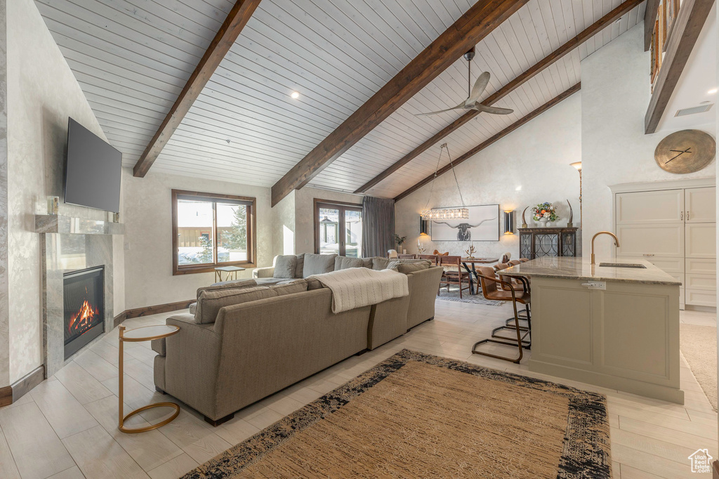 Living area with a high end fireplace, wood ceiling, and a ceiling fan