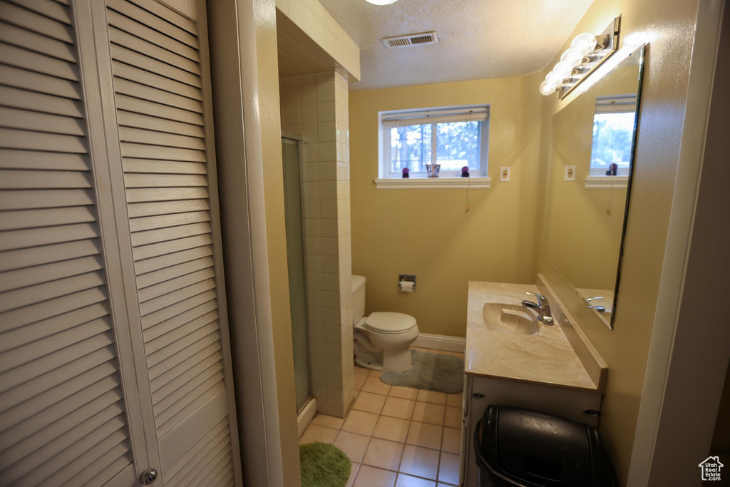 Bathroom featuring vanity, tile patterned floors, toilet, and walk in shower