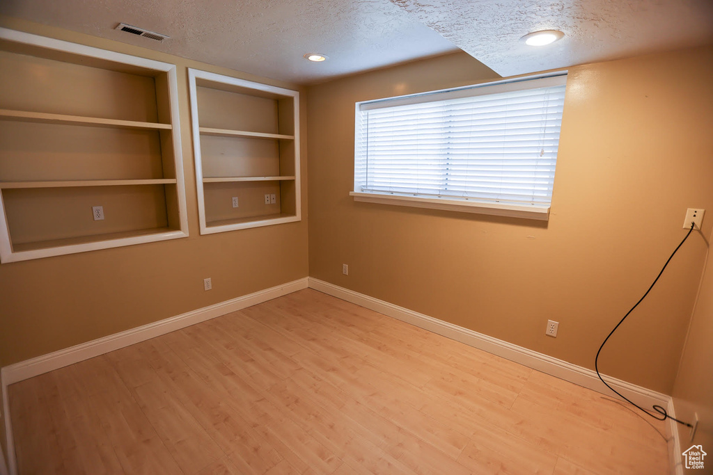 Spare room featuring hardwood / wood-style flooring, built in features, and a textured ceiling