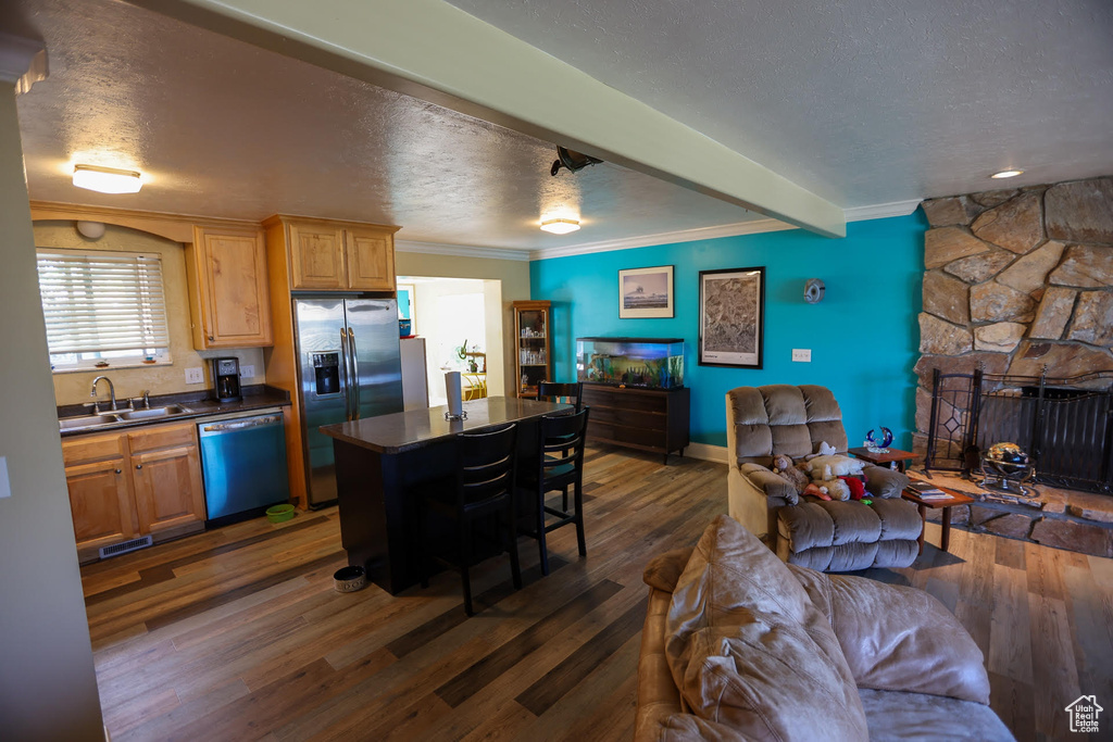 Kitchen with sink, a breakfast bar area, a center island, appliances with stainless steel finishes, and dark hardwood / wood-style floors