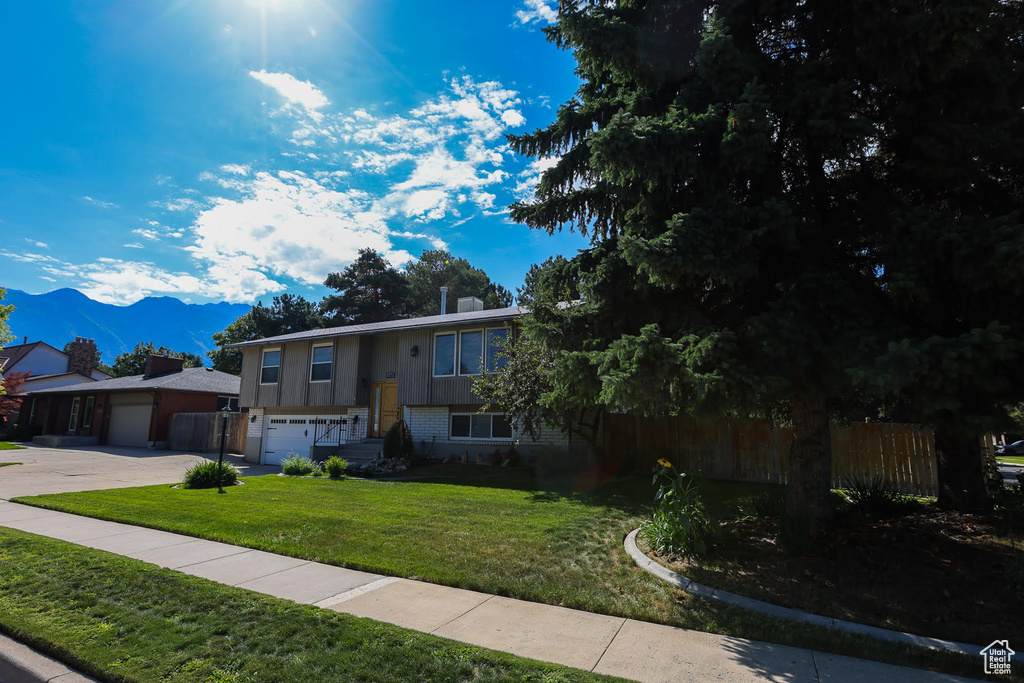 View of front of house featuring a garage, a mountain view, and a front lawn
