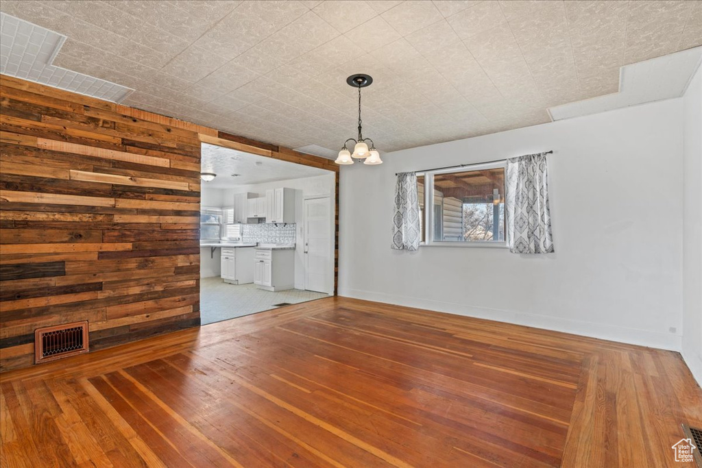 Interior space featuring a notable chandelier, wood-type flooring, and wood walls