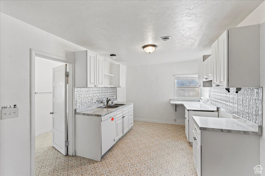 Kitchen with white cabinetry, sink, decorative backsplash, white dishwasher, and a textured ceiling