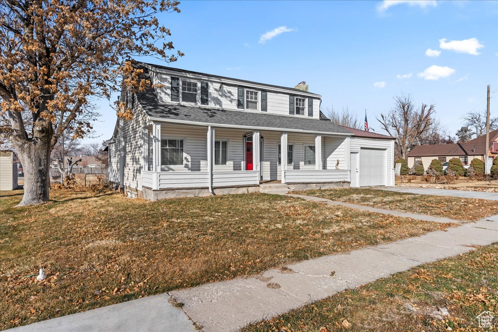 View of front of property with a porch, a garage, and a front lawn