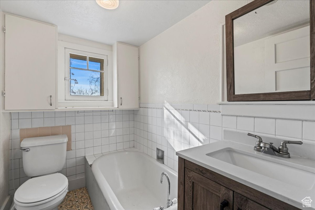 Bathroom with vanity, toilet, tile walls, and a tub