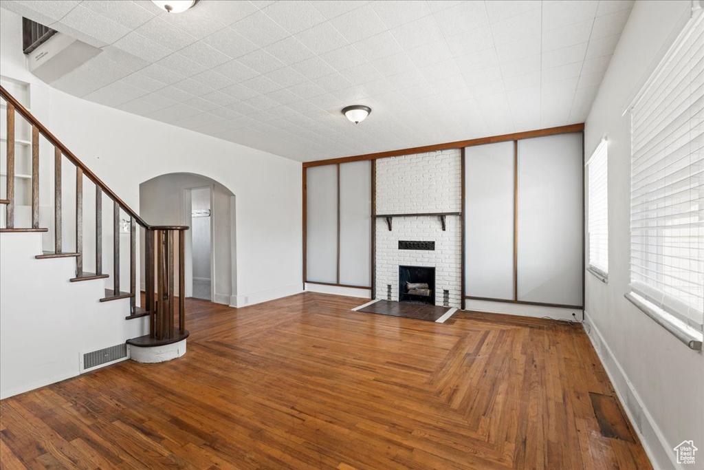 Unfurnished living room with a brick fireplace and hardwood / wood-style floors