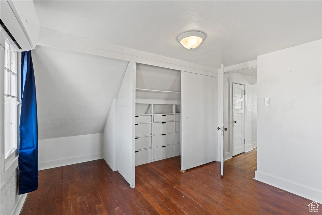 Unfurnished bedroom with dark wood-type flooring, a closet, and vaulted ceiling