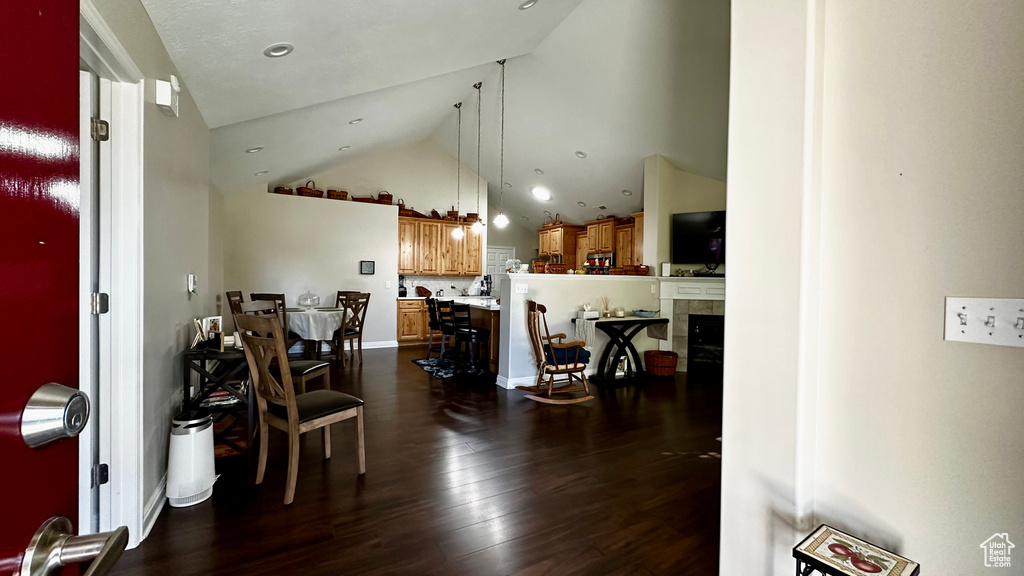 Dining room featuring high vaulted ceiling, a fireplace, and dark hardwood / wood-style flooring