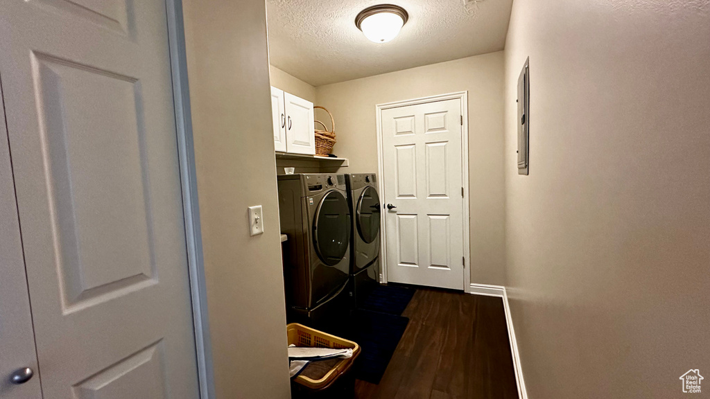 Laundry area featuring cabinets, dark hardwood / wood-style flooring, washer and dryer, and a textured ceiling