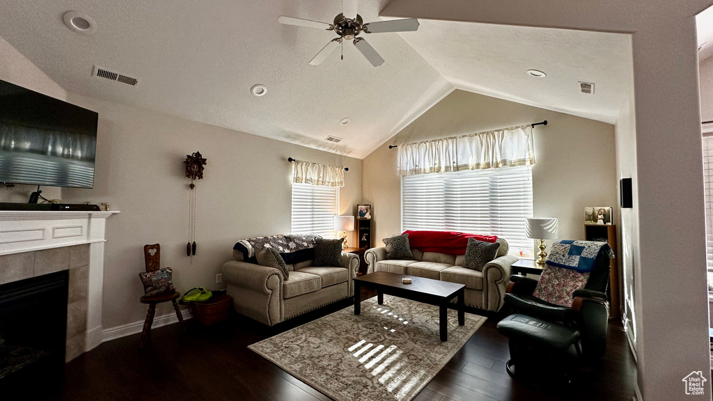 Living room with ceiling fan, a fireplace, lofted ceiling, and dark hardwood / wood-style floors