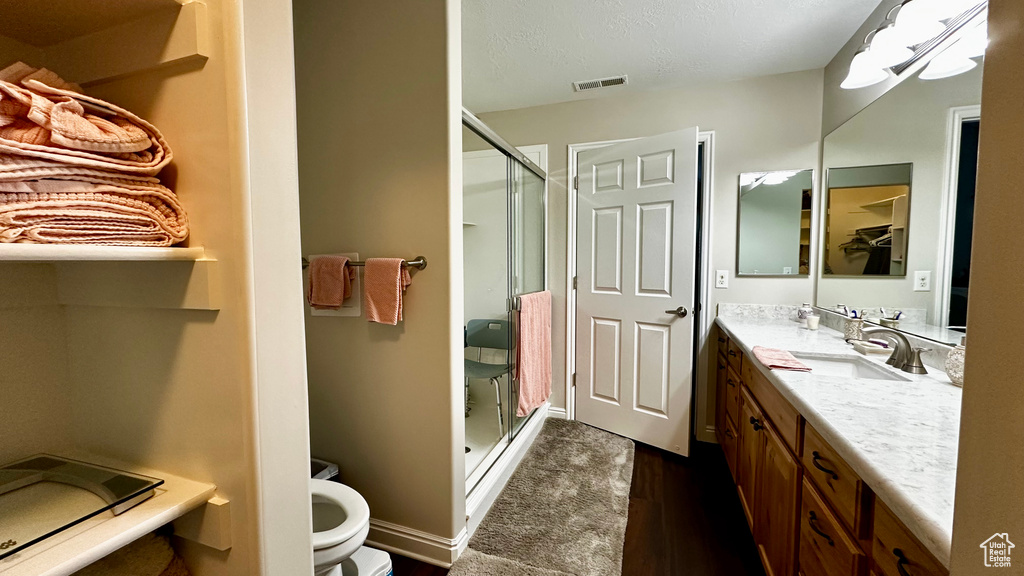 Bathroom with a shower with door, wood-type flooring, vanity, and toilet