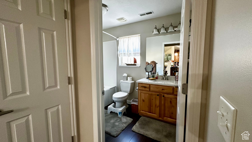 Full bathroom with vanity, hardwood / wood-style flooring, toilet, and washtub / shower combination