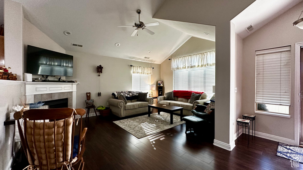 Living room with a tile fireplace, vaulted ceiling, dark hardwood / wood-style floors, and ceiling fan