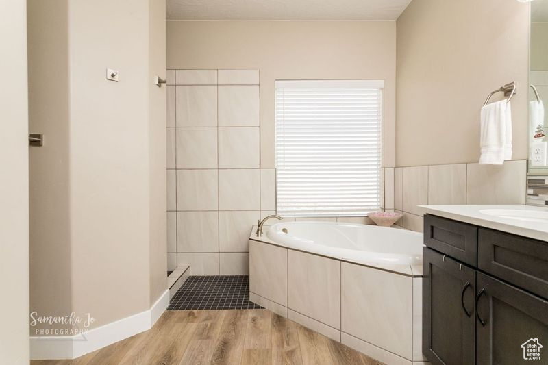 Bathroom with vanity, a bathtub, hardwood / wood-style flooring, and tile walls