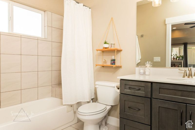 Full bathroom with vanity, shower / bath combination with curtain, and toilet