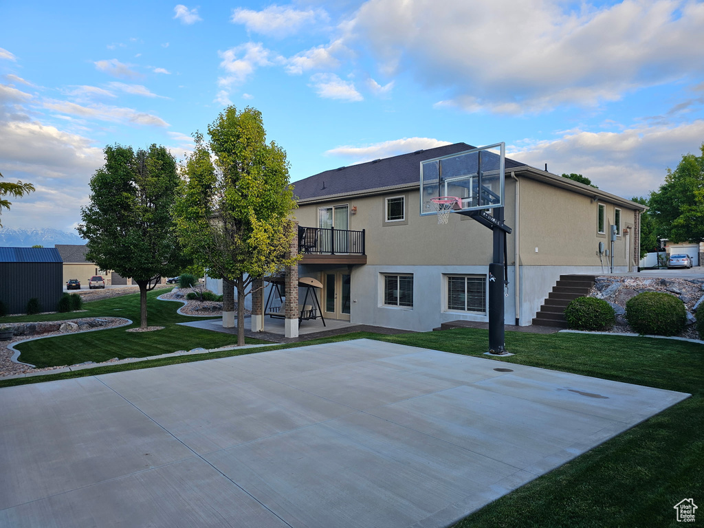 View of basketball court with stairs, a lawn, and basketball court