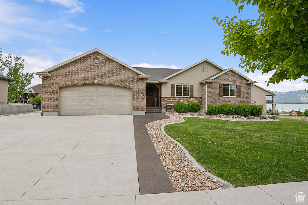 View of front facade featuring driveway, stucco siding, a front yard, and a garage