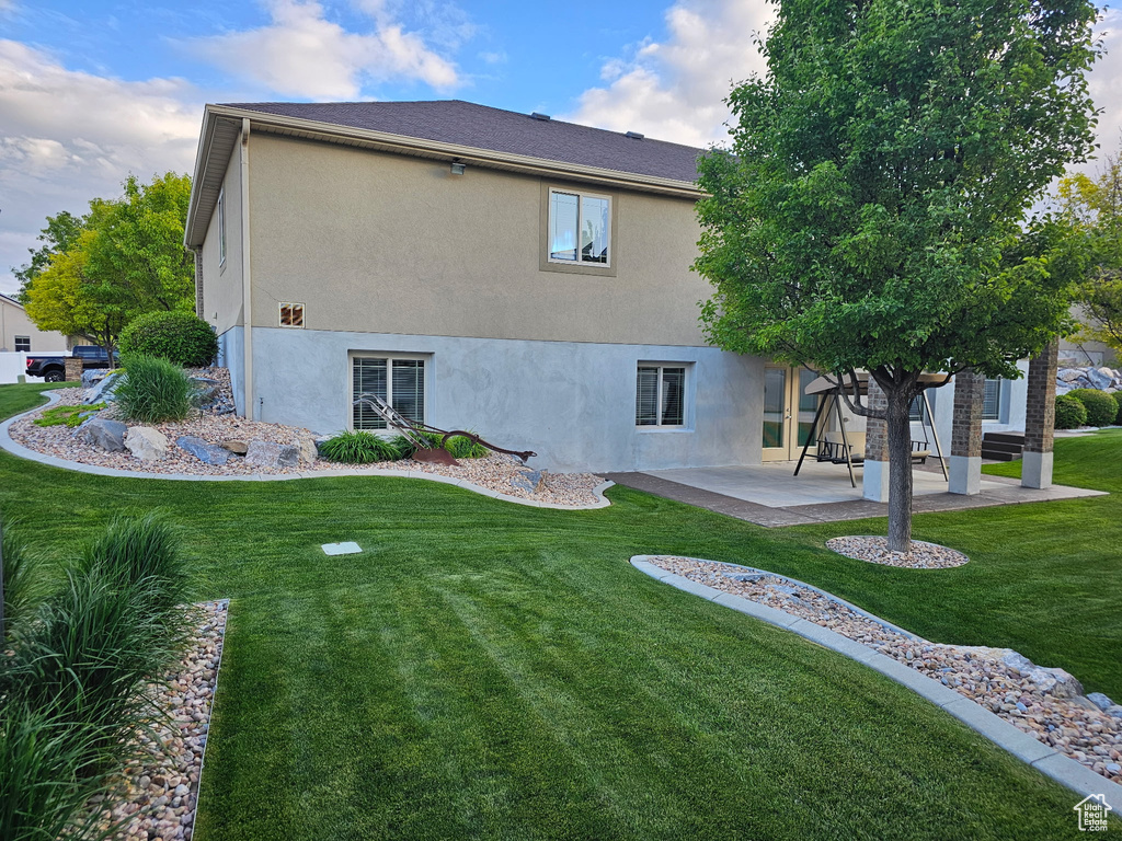 Rear view of house featuring a patio, stucco siding, and a lawn