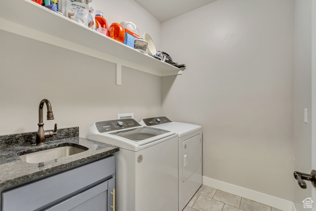 Washroom featuring sink, light tile patterned floors, and independent washer and dryer