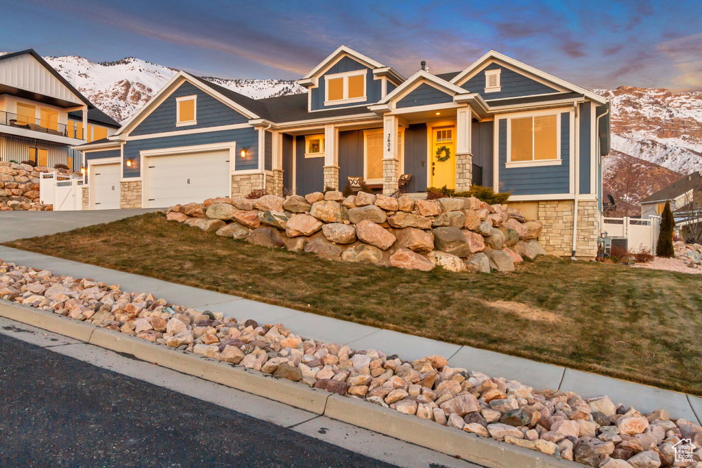 Craftsman-style home with central AC, a garage, a mountain view, and a lawn
