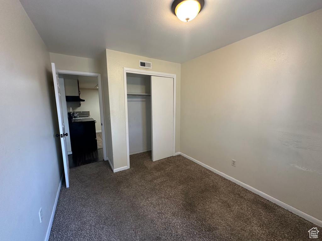 Unfurnished bedroom with dark colored carpet and a closet