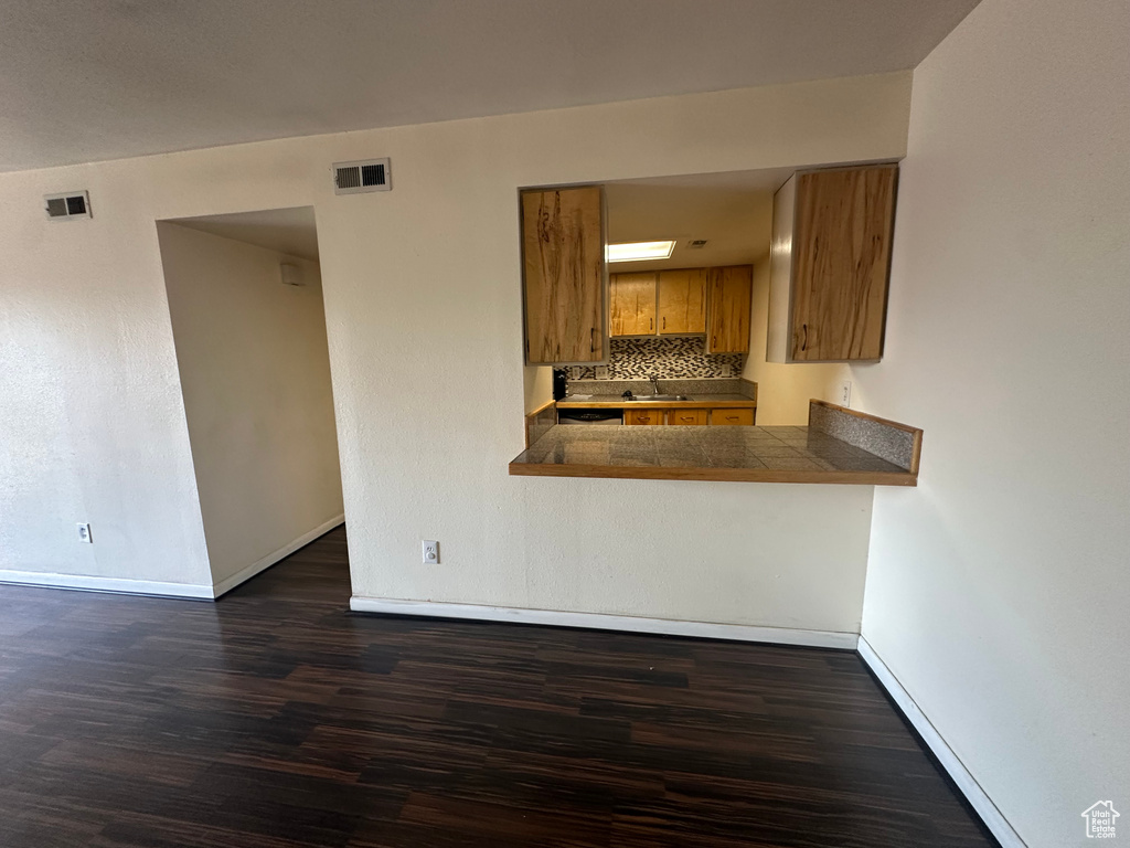 Kitchen with dark hardwood / wood-style flooring, backsplash, sink, and kitchen peninsula