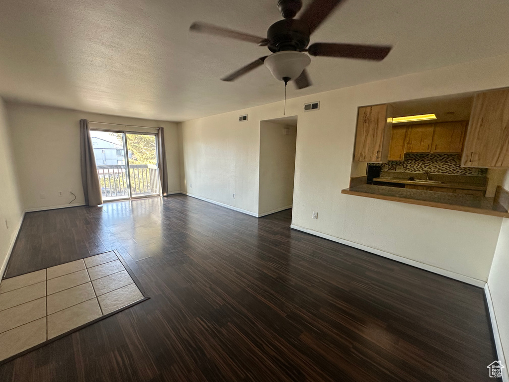 Unfurnished living room with dark wood-type flooring, ceiling fan, sink, and a textured ceiling