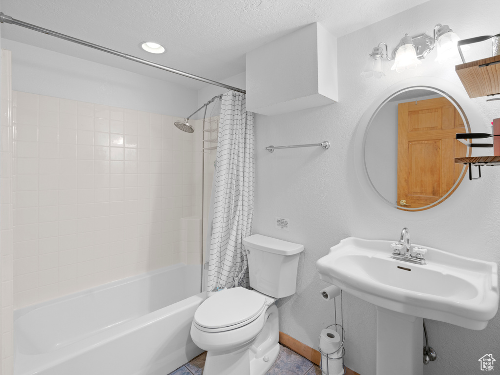 Bathroom featuring shower / bath combo with shower curtain, toilet, tile patterned flooring, and a textured ceiling