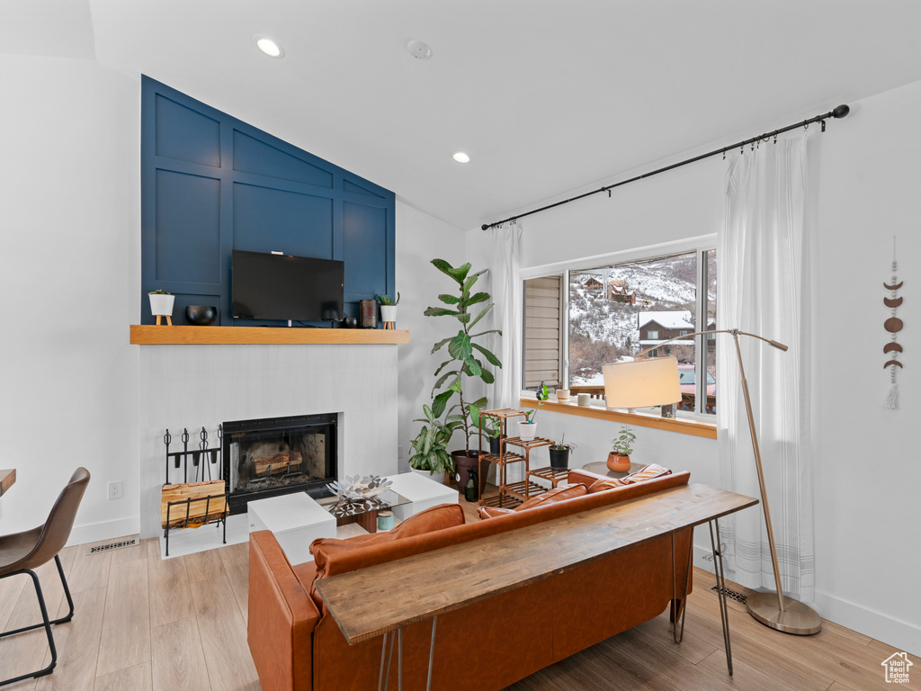 Living room with light hardwood / wood-style flooring and vaulted ceiling