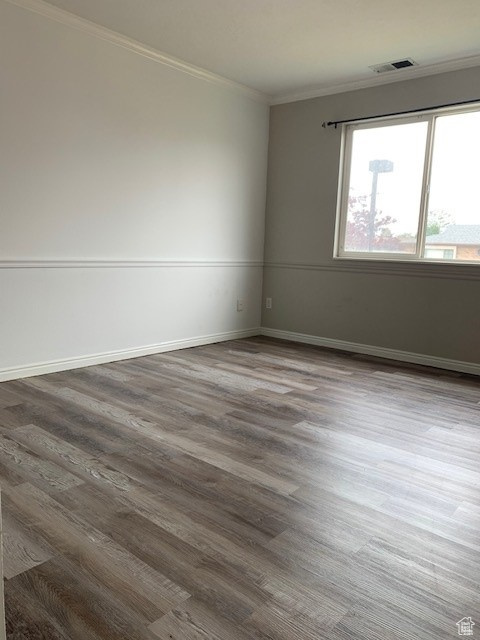 Spare room featuring ornamental molding, wood finished floors, and baseboards