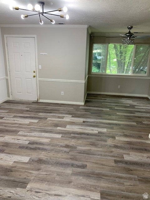 Unfurnished room with a chandelier, ornamental molding, wood finished floors, and baseboards
